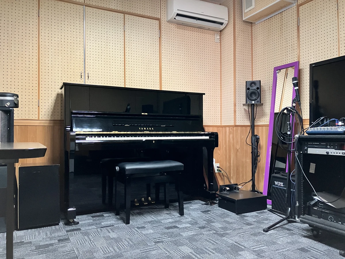 アップライトピアノと音響機材を備えたSGM松山本校のスタジオ